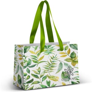 A small paper bag featuring a full-colour design of green leaves, with a green ribbon handle and a logo.