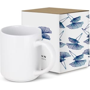 A stackable white coffee mug next to a decorative box featuring blue floral designs. The box has a logo.
