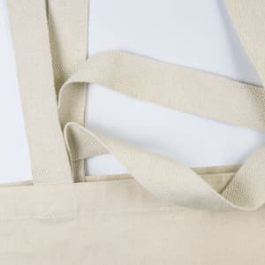 A beige tote bag with textured straps and a simple design, featuring a logo.