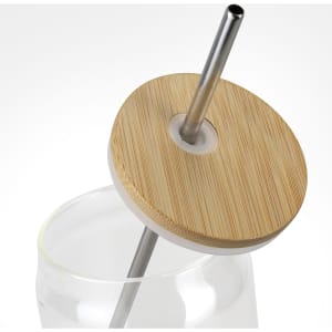 A glass tumbler with a bamboo lid and metal straw. The tumbler is partially filled with water.