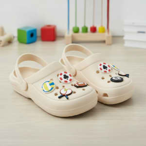 A pair of beige clogs adorned with colourful shoe charms, including a football and a panda.