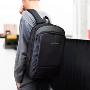 A black Kaden Soft Touch Backpack, carried by a person, featuring a logo and a sleek design.