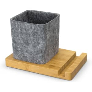 A grey felt phone stand desk caddy sits on a wooden bamboo base. The design is simple and modern.