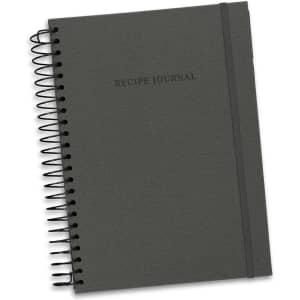 A dark grey recipe journal with a spiral binding and an elastic band, featuring the text "Recipe Journal" on the cover.