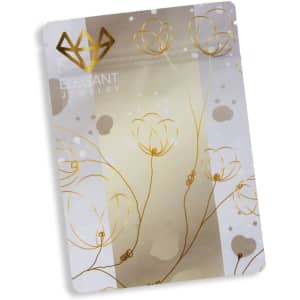 A small, metallic stand-up pouch in silver and gold, featuring floral designs and a logo.