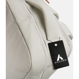 A light grey backpack with a handle and a tag attached, featuring a logo.