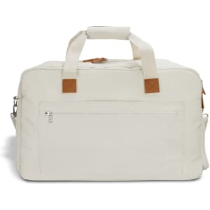 A cream duffle bag with tan accents, featuring a zippered front pocket and sturdy handles.