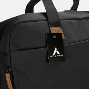 A black duffle bag with a leather tag and a logo, featuring sturdy handles and a sleek design.