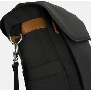 A black messenger bag with a brown strap and silver hardware, featuring a zip and side pocket detail.