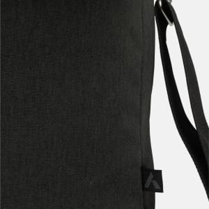 A black messenger bag with a textured surface, featuring an adjustable strap and a logo on the side.