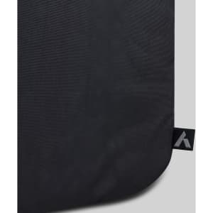 A close-up of a black fabric travel backpack featuring a logo tag on the edge.