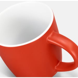 A red coffee mug with a matte finish and a white interior, featuring a handle and a branding logo.