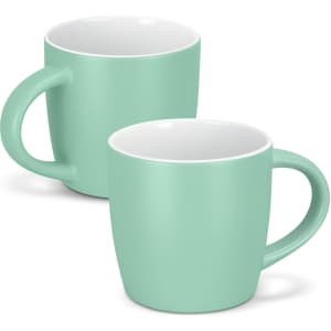 A drinkware set featuring two mint green coffee mugs with white interiors and round handles. One mug is slightly behind the other.