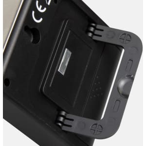 A black kitchen timer with a stand, featuring a metallic back and a small flip cover. It has a logo on the side.
