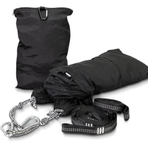 A black outdoor hammock with straps and carabiners, neatly packed in a matching storage bag.