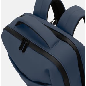 A navy blue soft-touch daily backpack with black zippers and padded straps. It features a sleek design.