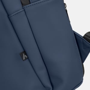 A navy blue soft-touch daily backpack featuring multiple pockets and a logo on the side.
