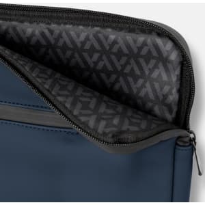 A navy soft-touch laptop sleeve features a grey zipper and a patterned interior lining. It includes branding.