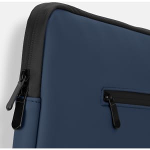 A navy blue soft-touch laptop sleeve with a black zipper detail and a logo on the front.