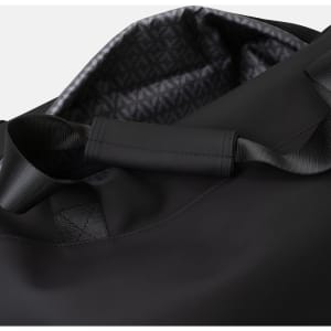 A black soft-touch duffle bag with a patterned interior and sturdy handles. It features a minimalist design and branding.