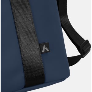 A soft-touch cooler bag in navy blue with a black strap and a small logo on the side.