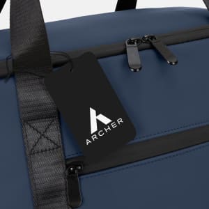 A soft-touch cooler bag in navy blue with a black tag and zippered compartments. The bag features a logo.