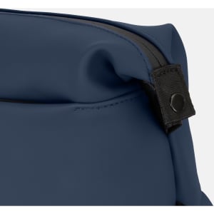 A toiletry bag in navy blue with a black zipper and a snap button detail. It features a sleek, soft-touch material.