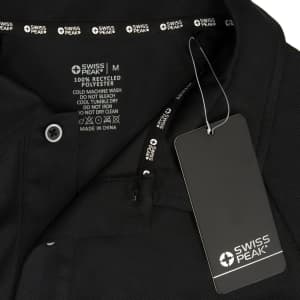 A black unisex polo shirt with care instructions and a tag, featuring a logo.