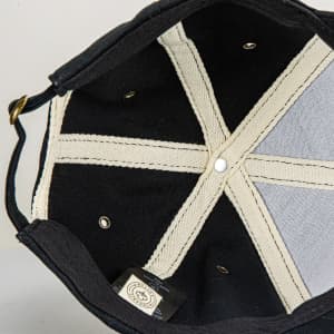 An organic cap featuring a black exterior with a light-coloured lining and internal stitching details.