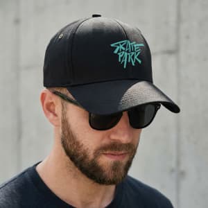 A black cap with a turquoise logo, featuring a curved brim and ventilation holes, worn by a man with sunglasses.