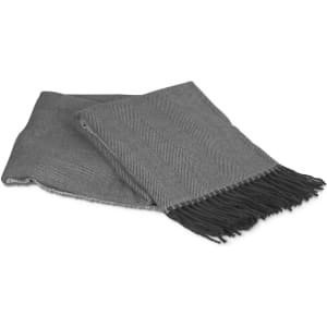 A soft grey throws blanket with a herringbone pattern and fringed edges, neatly folded.