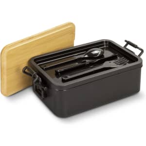 A black expandable lunch box with a bamboo lid, containing utensils: a spoon, fork, and knife.