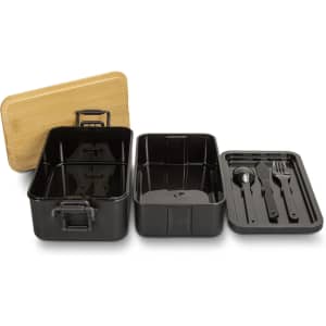 A black expandable lunch box with a bamboo lid, featuring two compartments and cutlery inside.