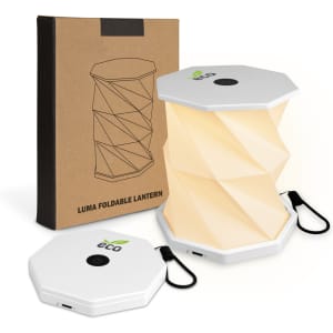 A foldable lantern in white with a USB charging port, displayed next to its box featuring a logo.