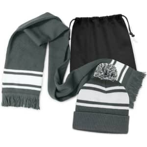 A grey scarf with white stripes and a matching grey beanie with a pom pom, packaged in a black drawstring bag.