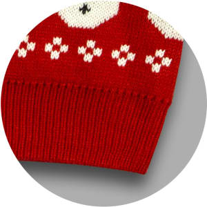 A red knitted jumper featuring white patterns, with a ribbed hem and a logo present on the fabric.