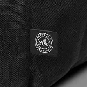 A black backpack made from recycled ocean plastic with a small logo patch.