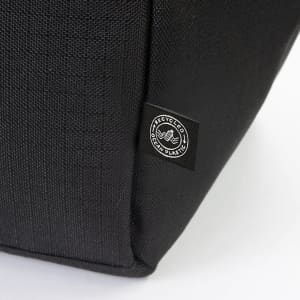 A black cooler bag featuring a logo, made from recycled materials. The textured fabric is visible in the image.