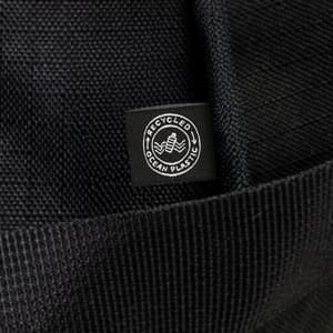A black duffle bag made from recycled ocean plastic, featuring a small logo tag.