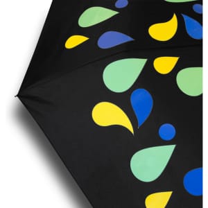 A compact umbrella featuring a black canopy adorned with colourful droplets in green, yellow, and blue. It has a branding logo.