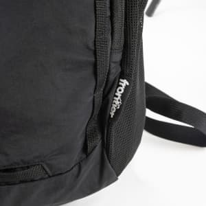 A black daypack with mesh detailing and a logo on the side. The straps are partially visible.