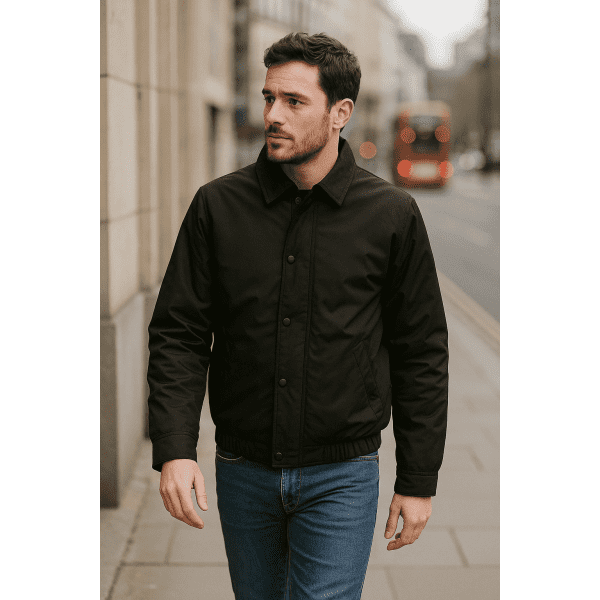 A man in a black contrast jacket walks along a city street. The jacket features a collar and buttons.