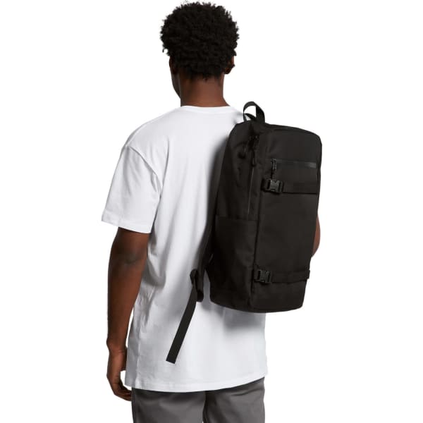 A black recycled strap backpack is worn on the back of a person, who is facing away, dressed in a white t-shirt.