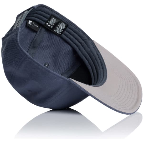 A navy cap with a grey brim, featuring an inner label and a logo. The cap is positioned at an angle.
