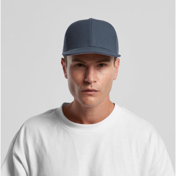 A blue cap with a structured design and a logo, worn by a model in a plain white shirt.