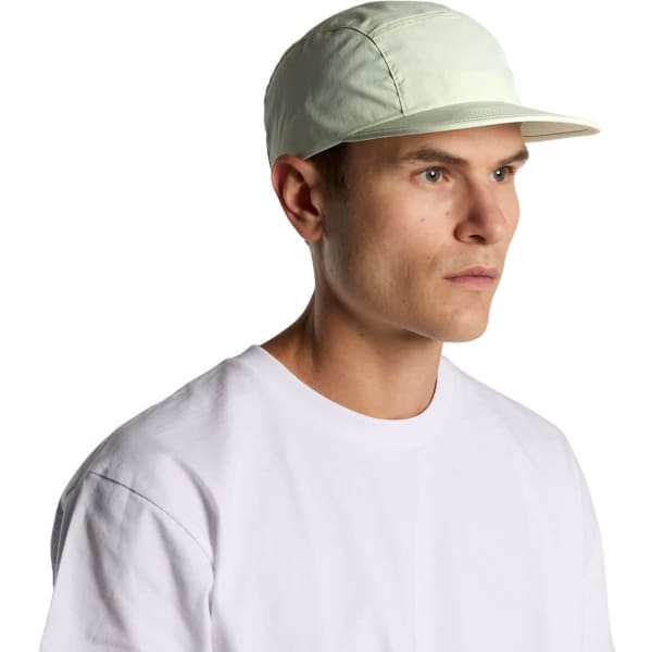 A light green nylon cap with a flat brim, featuring a logo, worn by a model in a white t-shirt.