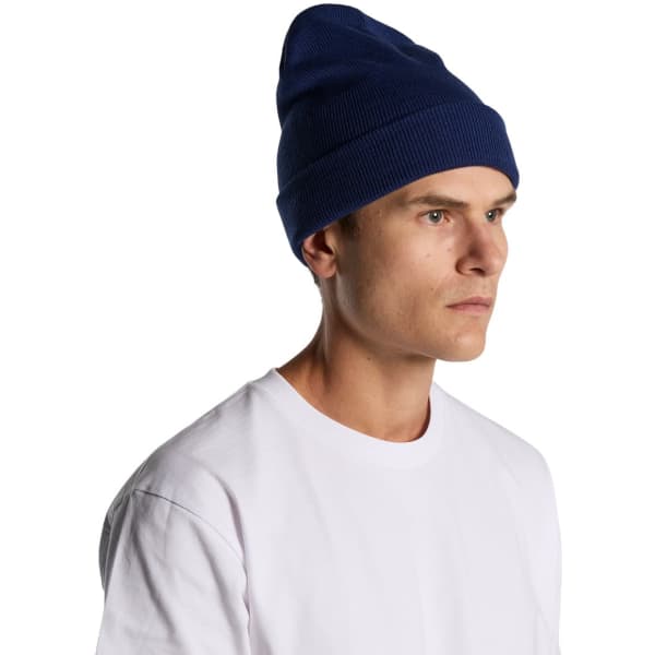 A navy cuff beanie worn by a person, featuring a ribbed texture and a logo.