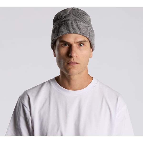 A grey knit beanie being worn by a model in a plain white T-shirt against a neutral background.