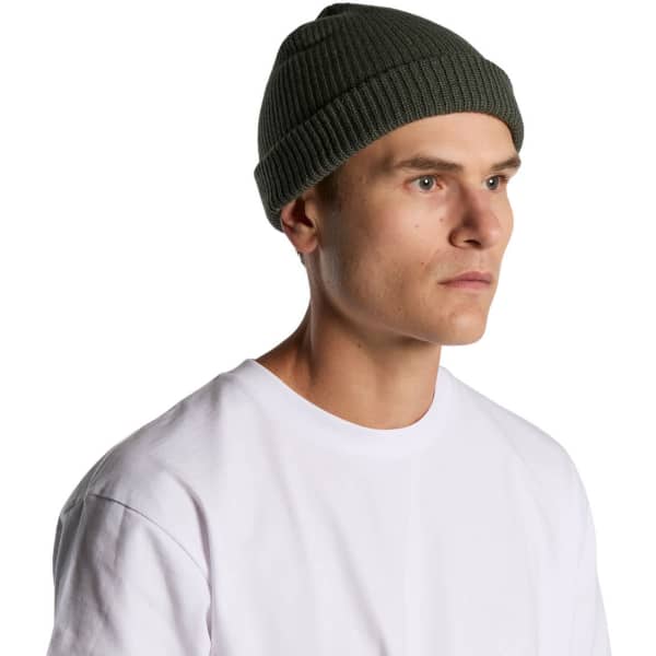 A green ribbed beanie worn by a man, featuring a snug fit and a logo on the side.