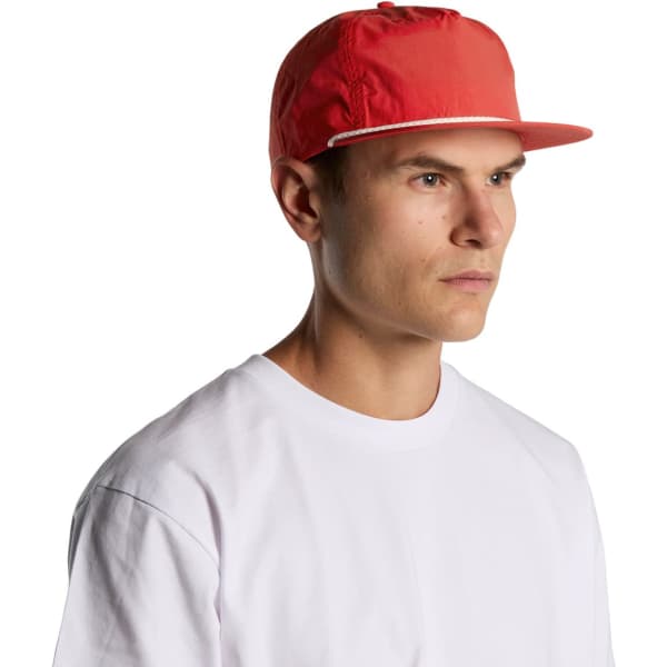 A red cap with a flat brim, featuring a logo, worn by a man in a white t-shirt.